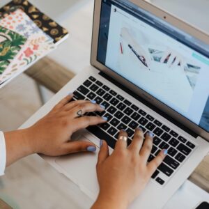Close-up of hands typing on a laptop at a stylish office desk with notebooks.